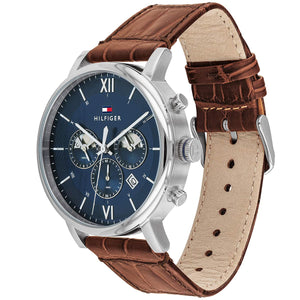 Angled profile right view of Tommy Hilfiger Evan Men's 1710393 watch showing polished round silver stainless steel case plain smooth bezel protective crown detailed integrated protected area and textured rich brown genuine calfskin leather strap with white contrast stitching dynamic visually casual utility visual dynamic visual style visual dynamic visual utility dynamic casual utility