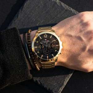 Close up of Tommy Hilfiger Luca 1710511 men's quartz battery watch on wrist showing black multi-function dial and gold metal bracelet