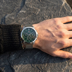 Close up of Tommy Hilfiger Henry 1710686 men's quartz battery watch on wrist showing emerald green skeleton dial and silver link bracelet