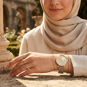 Elegant woman wearing Tommy Hilfiger 1782606 women's quartz battery watch with gold case and luxury gold floral dial