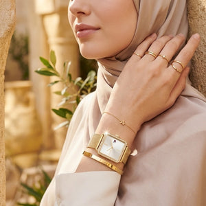 Elegant woman wearing Tommy Hilfiger Tea 1782829 women's quartz battery watch with gold case and luxury square mesh strap