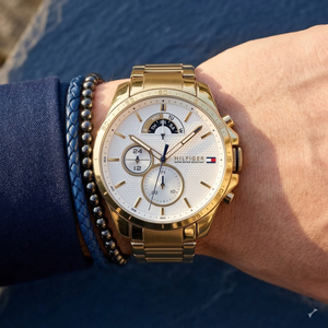 Close up of Tommy Hilfiger Decker 1791538 men's quartz battery watch on wrist showing white multi-function dial and gold metal bracelet