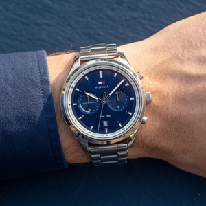 Close up of Tommy Hilfiger Bennett 1791725 men's quartz battery watch on wrist showing blue sunray dual-time dial and silver metal bracelet