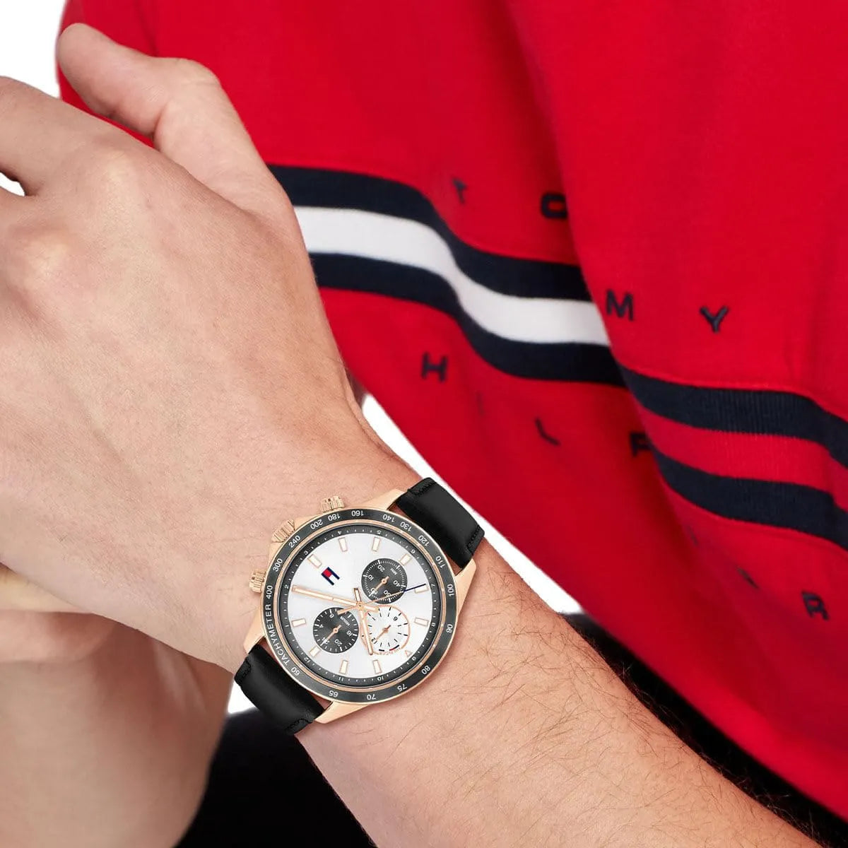 Close up of Tommy Hilfiger Miles 1792016 men's quartz battery watch on wrist showing white sunray dial and black leather strap