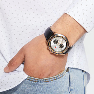Hand wearing a black wristwatch with a white face, against a light background.