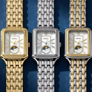 Three Fossil watches with different colored metal bands on a blue background