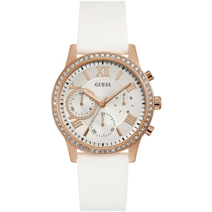 Guess Solar W1135L1 women's quartz battery multi-function watch with cushion-shaped rose gold-tone case, dynamic bezel embellished with crystals and screw details, deep silver-white dial with rose gold luminous indices, and integrated flexible pure white silicone rubber strap main view