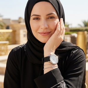 Elegant woman wearing Guess Sunrise W1135L5 women's multi-function gold watch with black rubber strap, adding distinctive casual luxury style