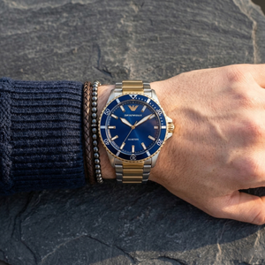 Elegant man wearing Emporio Armani World Explorer AR11682 men's quartz battery watch with two-tone case and luxury diver style