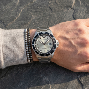 Close up of Emporio Armani World Explorer AR11683 men's quartz battery watch on wrist showing silver sunray dial and silver metal bracelet