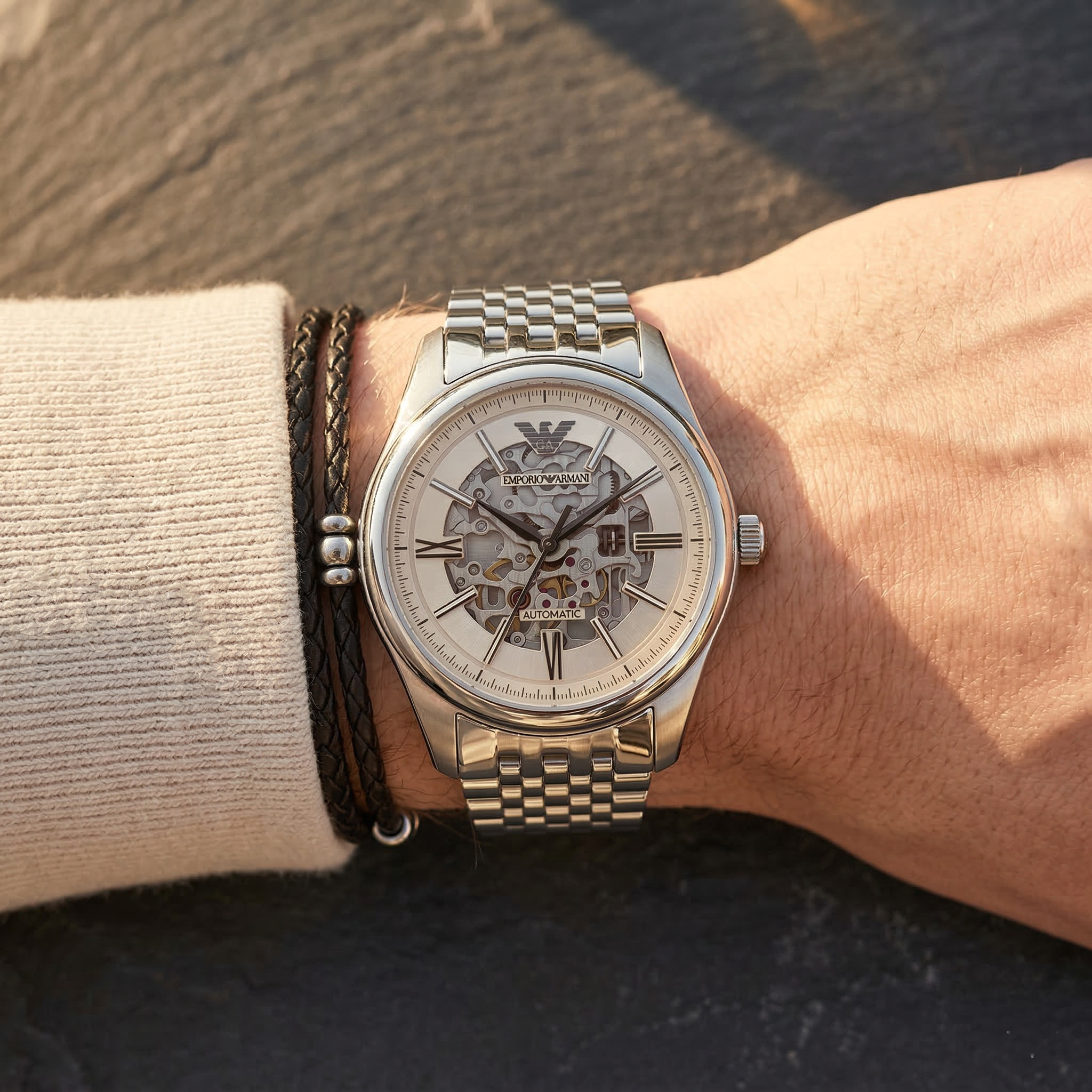 Close up of Emporio Armani Antonio AR60095 men's automatic watch on wrist showing intricate beige skeleton dial and silver metal bracelet