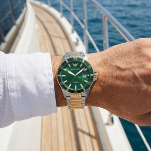 Man wearing Emporio Armani AR80063 green and gold diver watch on a yacht