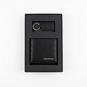 Live smartphone photograph of the Armani Exchange AX mirror original 2-piece gift set showcasing the black leather wallet with silver logo and matching metal keychain inside the custom black and red box