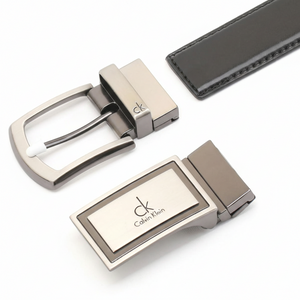 Detailed view of a Calvin Klein black leather belt presented with its two interchangeable designer buckles: a modern logo plaque and a signature pin buckle