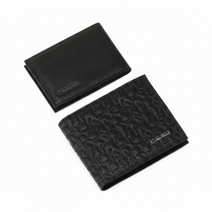 Top-down view of a Calvin Klein men's black leather wallet featuring an all-over embossed CK monogram pattern and a silver metal logo, displayed next to its removable card case insert