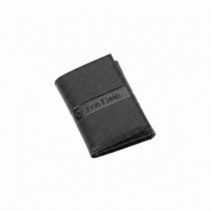 Angled high view of a closed Calvin Klein men's black saffiano leather wallet featuring a smooth horizontal band with a debossed Calvin Klein logo