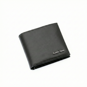 Angled high-perspective view of a closed Calvin Klein men's black smooth leather wallet highlighting the elegant minimalist design and silver metal logo hardware