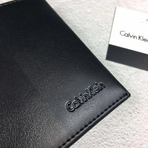 Close-up high-angle view of a Calvin Klein men's black leather wallet showcasing the stylish matte vertical stripe pattern and the small debossed Calvin Klein logo