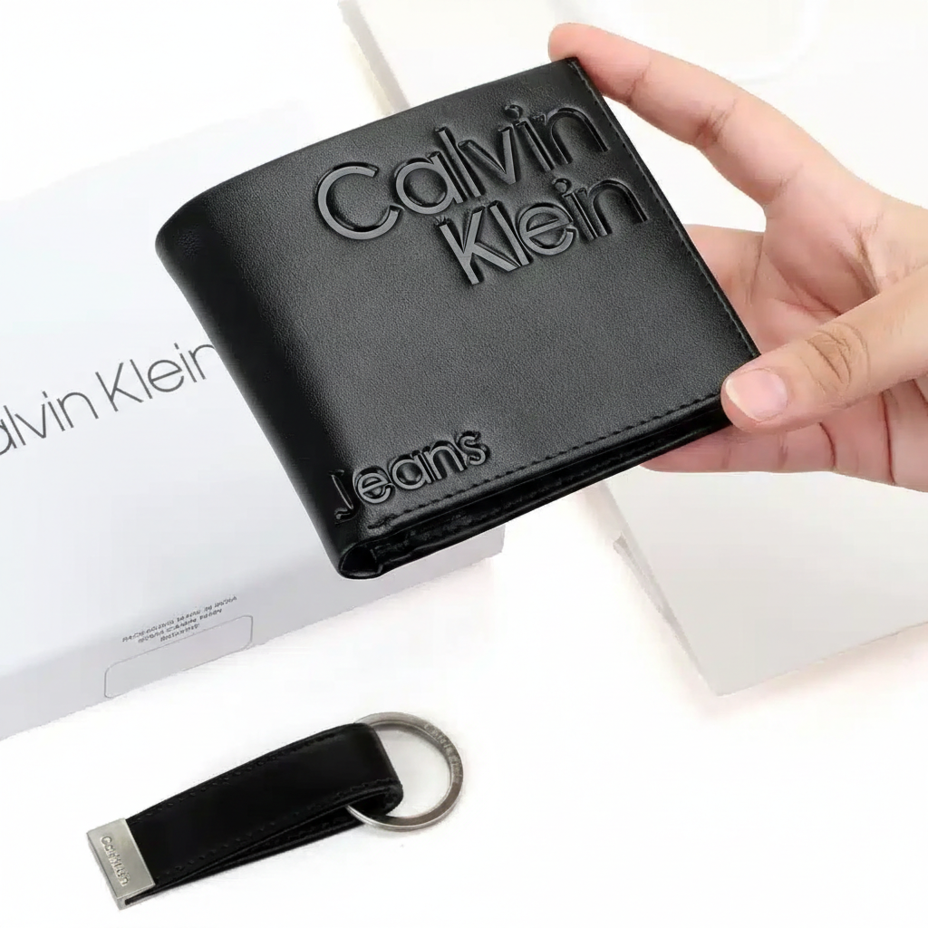Calvin Klein Jeans men's accessory gift set including a black leather bifold wallet and a designer keychain, shown next to the original white branded presentation box