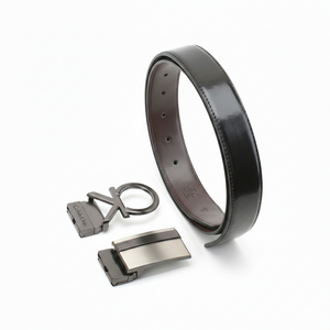 Top-down view of a Calvin Klein men's reversible leather belt gift set featuring the brown side and two premium metal buckles including an oversized cK monogram plaque