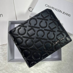 Calvin Klein men's black wallet with embossed monogram logo pattern and silver metal branding inside a white Calvin Klein Jeans gift box
