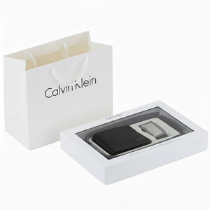Calvin Klein men's gift set featuring a black smooth leather wallet and belt in a white branded box next to a Calvin Klein gift paper bag