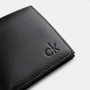 Macro close-up studio shot focusing on the small debossed ck logo accent over the black smooth genuine leather surface