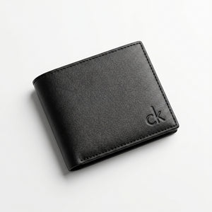 Macro close-up studio shot focusing on the small debossed ck logo accent over the black smooth genuine leather surface
