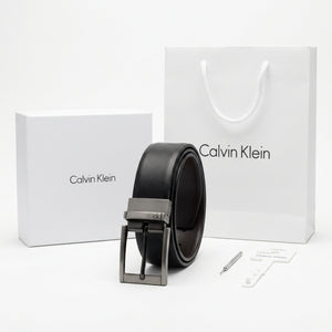 Top-down style studio product photography of the Calvin Klein mirror original reversible black leather belt neatly rolled with buckle centered