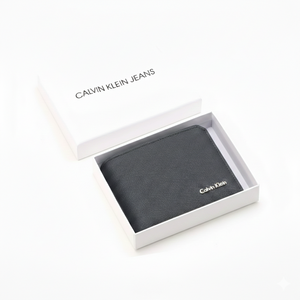 Angled view of a Calvin Klein men's navy blue saffiano leather wallet with a silver metal logo, beautifully presented inside an open white branded gift box