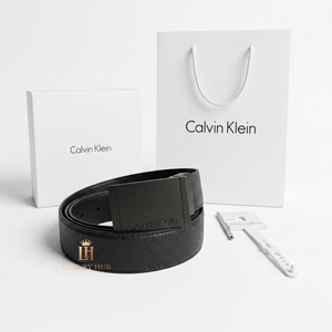 Professional standing view of the Calvin Klein black leather belt with matte buckle alongside original designer packaging
