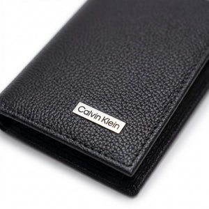Front view of the Calvin Klein black genuine leather wallet showing the classic silver metal logo and premium stitching