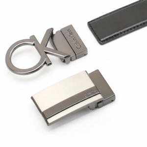 High-detail close-up of the two metal buckles in the Calvin Klein belt set, highlighting the embossed cK logo on the black leather strap and the polished gunmetal finish