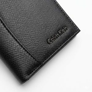 Straight front view product photography of the Calvin Klein black saffiano leather wallet showcasing the smooth engraved center logo band