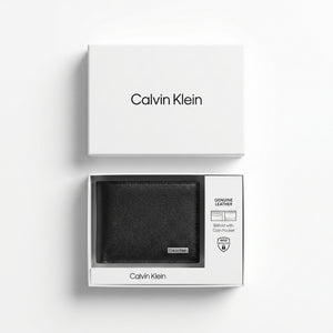 Top-down studio photograph of the Calvin Klein pebbled black leather wallet neatly placed inside its open premium white gift box