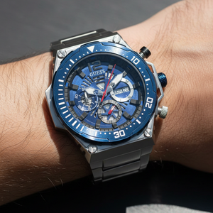 Close up shot of Guess Exposure GW0324G1 watch on wrist showing the intricate blue skeleton dial and gear bezel