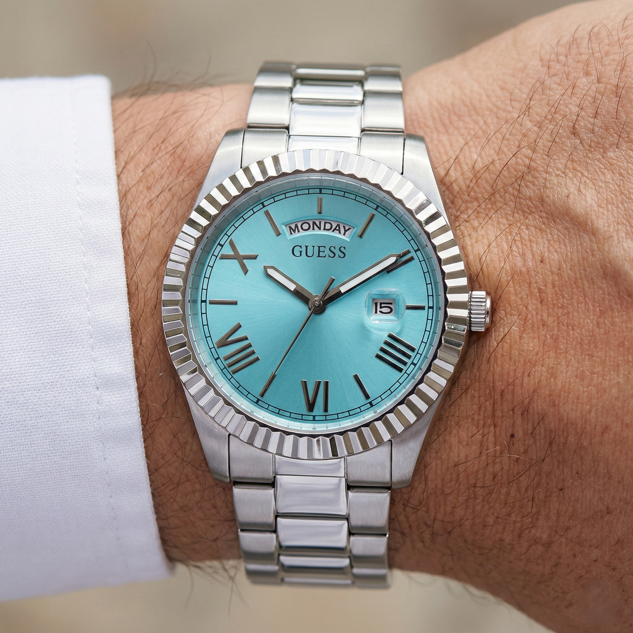 Close up shot of Guess GW0265G11 on wrist highlighting the turquoise sunray dial and day date window