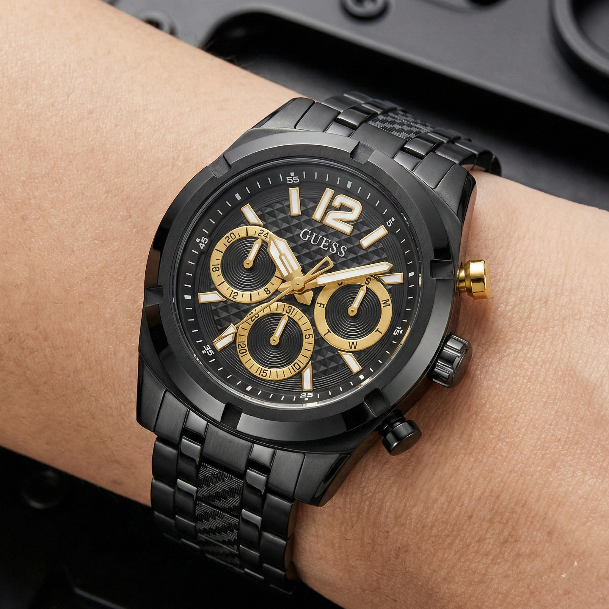 Detailed view of the black patterned dial and gold pushers of Guess GW0714G4