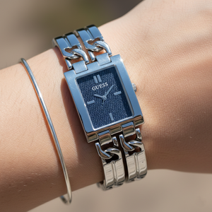 Close up shot of Guess GW0807L1 watch on wrist showing the blue denim dial and silver chain links