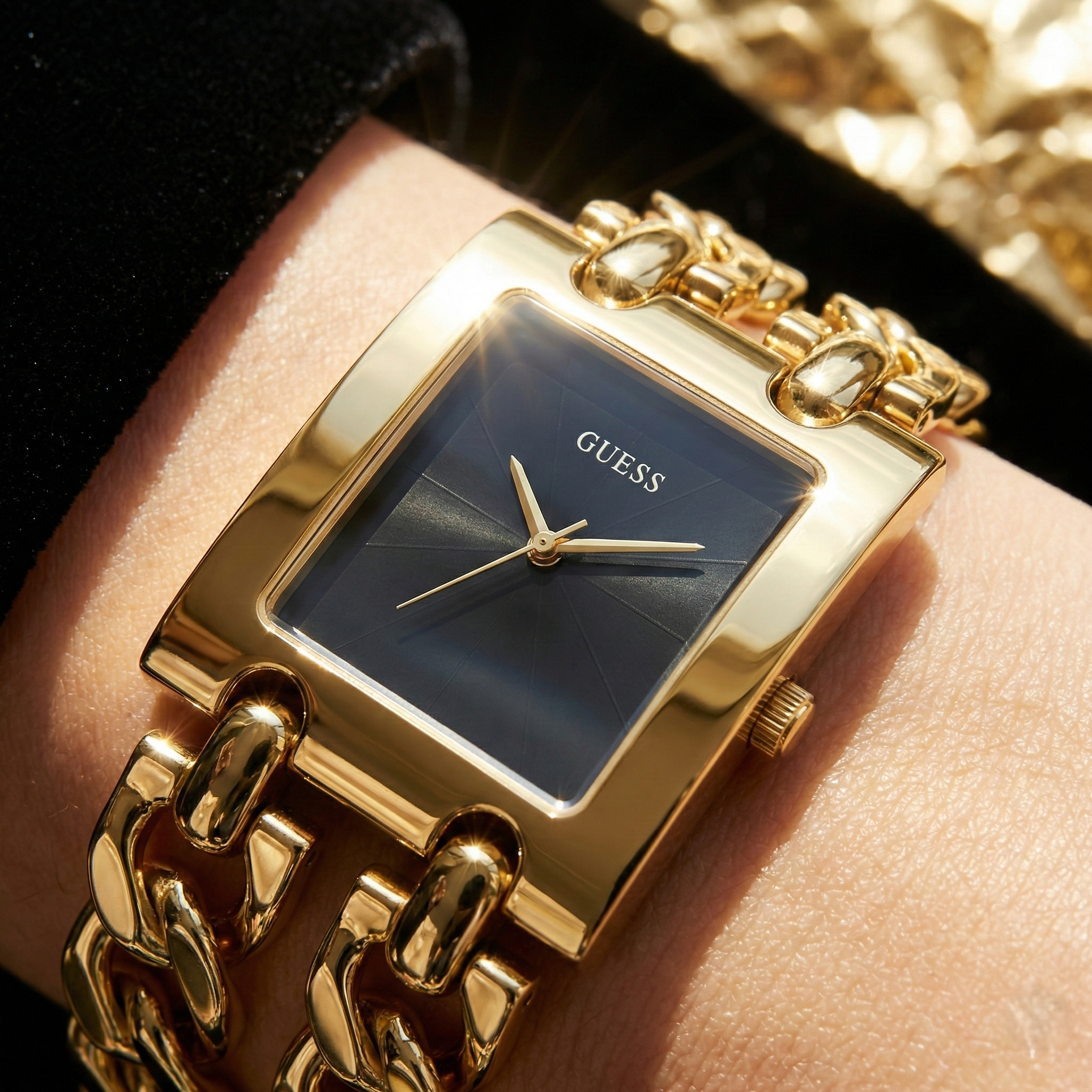 Close up shot of Guess U1117L5 watch on wrist showing the black minimalist dial and gold chain links