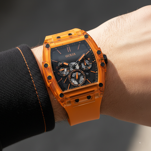 Close up shot of Guess Phoenix GW0203G10 watch on wrist showing the black multifunction dial and orange details