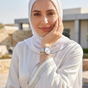 Half-face lifestyle shot of a woman with fair skin wearing bracelets and rings on the same hand as the Guess Montauk silver metal watch for a sophisticated everyday look