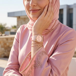 Half-face lifestyle shot of a woman with fair skin wearing bracelets and rings on the same hand as the Guess Limelight pink rubber watch for a sophisticated everyday look