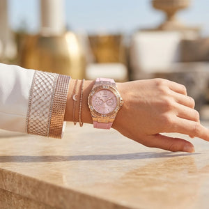 Close up shot of Guess W1053L3 on wrist showing the light pink dial with multi-function sub-dials and crystal bezel details