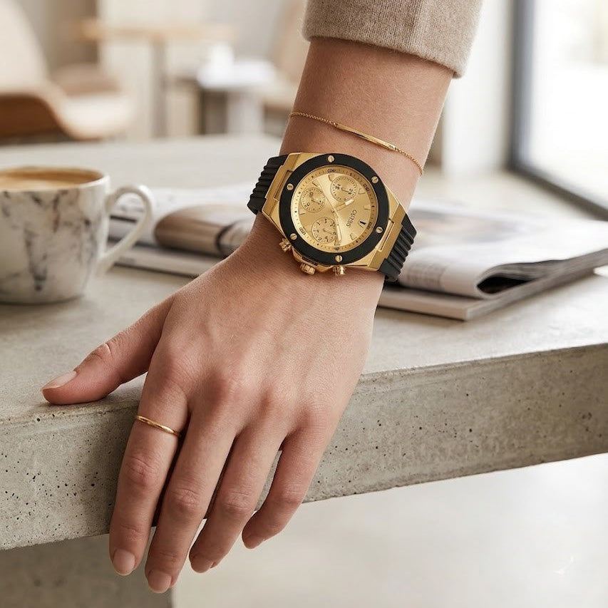Close up of Guess athena GW0030L2 women's quartz battery watch on wrist showing deep gold dial and luxury black bezel