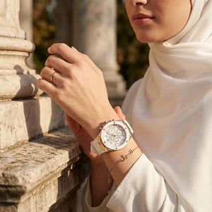 Elegant woman wearing Guess Athena GW0030L3 women's quartz battery watch with rose gold case and luxury white rubber strap