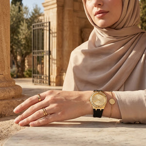 Elegant woman wearing Guess Cosmo GW0034L1 women's quartz battery watch with gold case and luxury black rubber strap