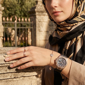 Elegant woman wearing Guess Venus GW0118L2 women's quartz battery watch with rose gold case and luxury black rubber strap