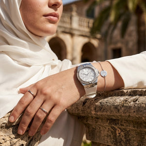 Elegant woman wearing Guess Venus GW0118L3 women's quartz battery watch with silver case and luxury white rubber strap