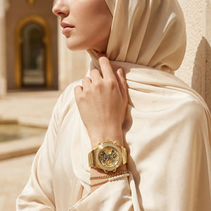 Elegant woman wearing Guess Fusion GW0552L2 women's quartz battery watch with gold case and luxury gold metal bracelet